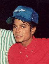 Kırmızı bir bluz ve mavi bir şapka takan bir adam gülümsüyor smiling